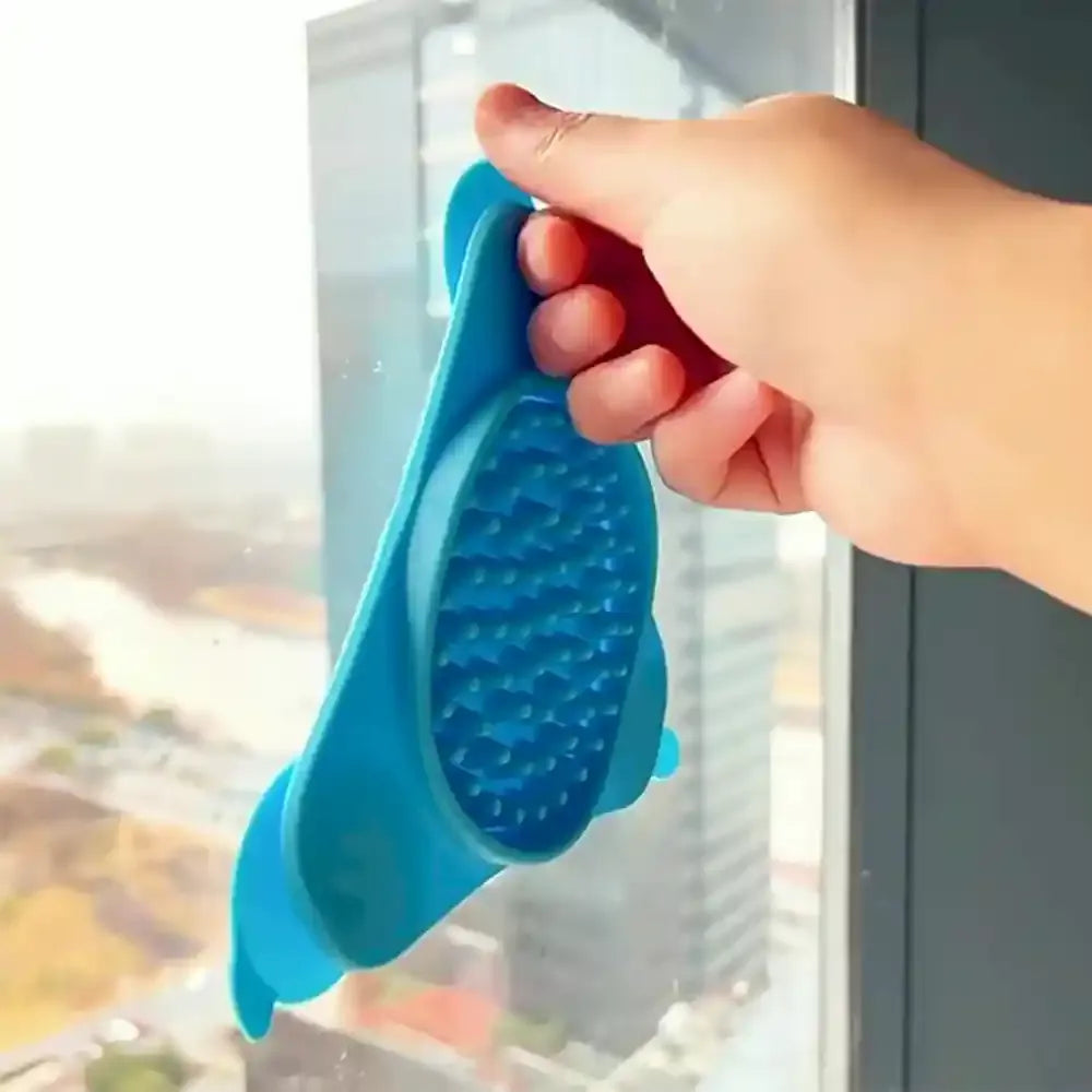 Hand attaching a blue silicone lick toy to a window