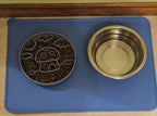 Pet food and water bowls on a blue mat with a wooden trim.
