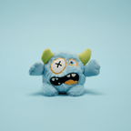Blue plush toy with green horns on a light blue background