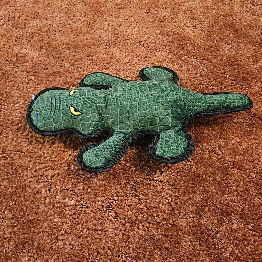 Green crocodile-shaped toy on a brown carpet surface
