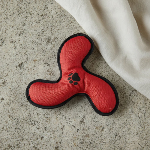 Red dog toy with black paw print on a concrete surface